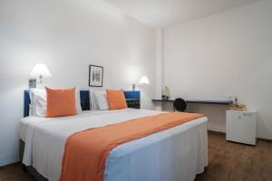 a bedroom with a large bed with orange and white pillows at Hotel Normandie - by Easy Hotéis in São Paulo