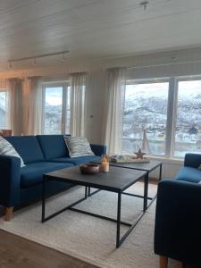 a living room with a blue couch and a coffee table at My Home Kaldfjorden in Tromsø