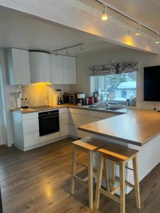 a kitchen with white cabinets and a wooden table at My Home Kaldfjorden in Tromsø