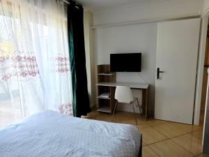 a bedroom with a bed and a desk and a television at Chambre B1 in Toulouse