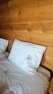a bed with white pillows and a wooden headboard at Memórias da Serra - Chalé Serra da Estrela Penhas da Saude in Penhas da Saúde