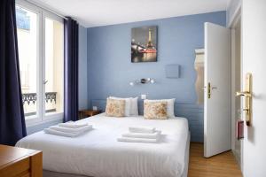パリにあるHôtel Apollo Opéraの青い壁と白いベッドのある寝室