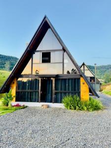 a house with a pitched roof on a gravel road at Chalè Aurora do vale in Cobras