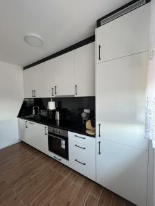 a kitchen with white cabinets and a black counter top at ESEM stan na dan in Modriča