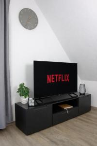 a black entertainment center with a clock on a wall at Ferienwohnungen Möhnesee - zentral, stilvoll und ruhig mit Balkon und Boxspringbetten in Möhnesee