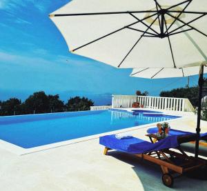 a swimming pool with an umbrella and a chair and a swimming pool at Villa Conte in Podstrana