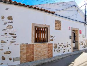 a white house with a wall with rocks on it at La Casita de Ale Casa Rural cerca Puy du Fou in Polán