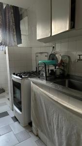 a kitchen with a sink and a stove top oven at Quarto privativo confortável próximo a ufba, praia, comercio e zoológico in Salvador +9 photos
