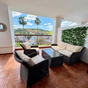 a living room with couches and a balcony with palm trees at Feel The Vibe Alcaidesa in La Alcaidesa