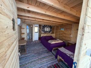 a room with a purple couch in a wooden room at Leley Camp in Nuweiba