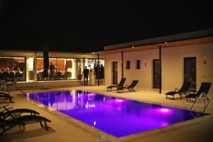 a swimming pool at night with purple lights at Poiana Events - Vilă privată cu piscină aproape de Mamaia și Constanța in Poiana