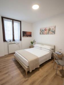 a white bedroom with a bed and a chair at Oasi Bernareggio Smart Work & Relax in Bernareggio