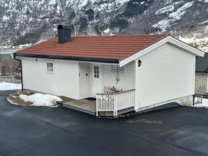 a small white house with a wooden porch at Koselig hus i Beisfjord in Narvik