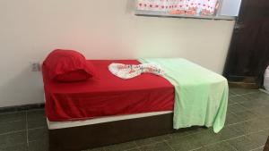 a small bed with a red blanket and a table at Casa de Mainha in Salvador