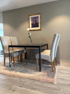a dining room table with two chairs and a vase with a flower at 4-Bedroom Accommodation Near NTNU & Raufoss Business Area in Gjøvik +6 photos