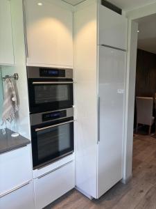 a white kitchen with two ovens and a refrigerator at 4-Bedroom Accommodation Near NTNU & Raufoss Business Area in Gjøvik