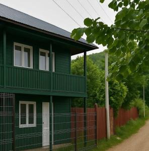 a green house with a fence in front of it at CABANUȚA de sub Masivul Penteleu in Varlămul