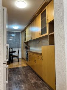 a kitchen with wooden cabinets and a dining table at Apartman 7 Foča in Foča +10 photos