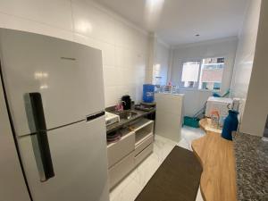 a white kitchen with a refrigerator and a counter at Atlântico 34 Guilhermina in Praia Grande