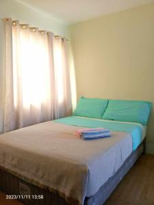a bedroom with a bed with blue sheets and a window at Hanna's Condo at Sanremo Oasis in Cebu City