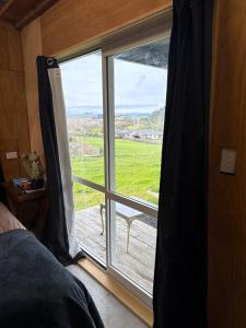 a bedroom with a window with a view of a field at Vineyard Cabin in Te Kauwhata +7 photos