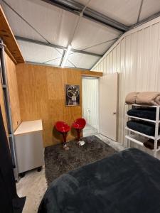 a bedroom with a bed and two red chairs at Vineyard Cabin in Te Kauwhata