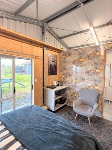 a bedroom with a large bed and a chair at Vineyard Cabin in Te Kauwhata