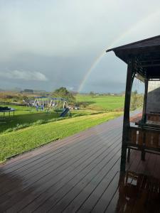a wooden deck with a playground with a rainbow in the background at Vineyard Cabin in Te Kauwhata