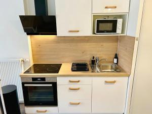 a small kitchen with a sink and a microwave at Lumen Chartrain - appartement proche centre-ville, balcon et parking in Chartres +17 photos