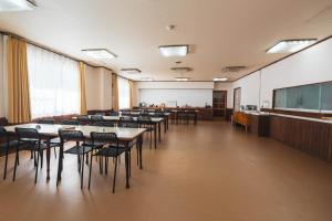 a large room with tables and chairs and a screen at Juniya Myoko in Myoko +48 photos