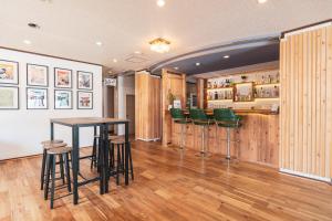 a bar with green stools and a table in a room at Juniya Myoko in Myoko