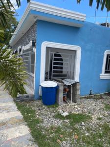 a blue house with a trash can in the doorway at Villa Rivera in Boca Chica +4 photos