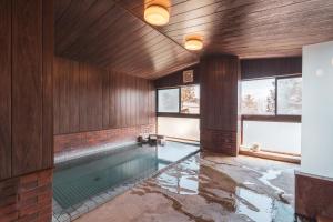 a swimming pool in a room with wooden walls at Juniya Myoko in Myoko