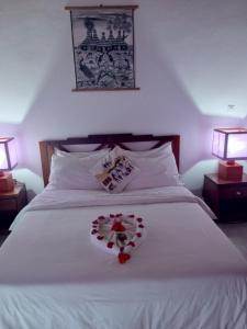 a bedroom with a white bed with a heart made out of roses at Escape villa assouinde in Assinie
