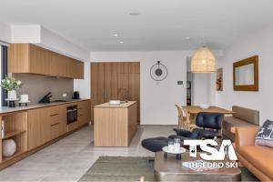 a living room with a couch and a kitchen at Black Bear 402 in Thredbo