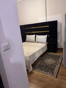 a bedroom with a bed with a black headboard and a rug at Le Nide d'azrou in Azrou