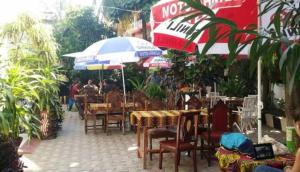 a restaurant with tables and chairs and umbrellas at Manch Lodge Vuga Zanzibar in Zanzibar City