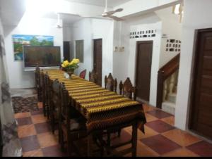 a room with a long table with chairs and a television at Manch Lodge Vuga Zanzibar in Zanzibar City