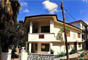 a white house with a tree in front of it at Manch Lodge Vuga Zanzibar in Zanzibar City