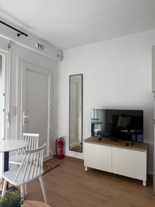 a white living room with a tv and a table and chairs at Green Almond D1 in Orfánion