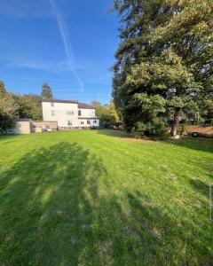 a large grassy field with a house in the background at Pet Friendly 2 Bed Ground Floor Apartment in Addlestone with Free Driveway Parking in Addlestone