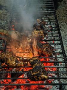 a bunch of meat on a grill with flames at Hijoltola Camping & Resort in Kumāran