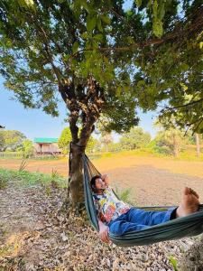 a man laying in a hammock under a tree at Hijoltola Camping & Resort in Kumāran +20 photos