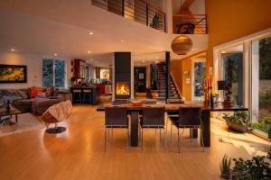 a living room with a table and chairs and a fireplace at Modern Glass House with Firepit, Views & Private Retreat in Elka Park