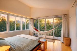 a bedroom with a hammock in a room with windows at Modern Glass House with Firepit, Views & Private Retreat in Elka Park +28 photos