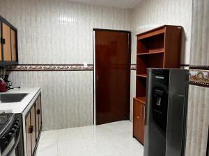 a kitchen with a black refrigerator and a wooden door at Apartamento Albergue - Buga in Buga