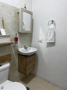 a bathroom with a sink and a toilet and a mirror at Apartamento Albergue - Buga in Buga