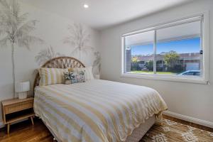 a bedroom with a bed and a window at Palms on Wunda in Sussex Inlet