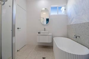 a white bathroom with a tub and a sink at Palms on Wunda in Sussex Inlet +17 photos