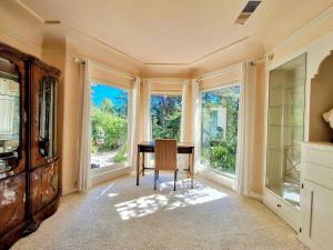 a dining room with a table and large windows at Fairy Hill Sanctuary in Monte Sereno